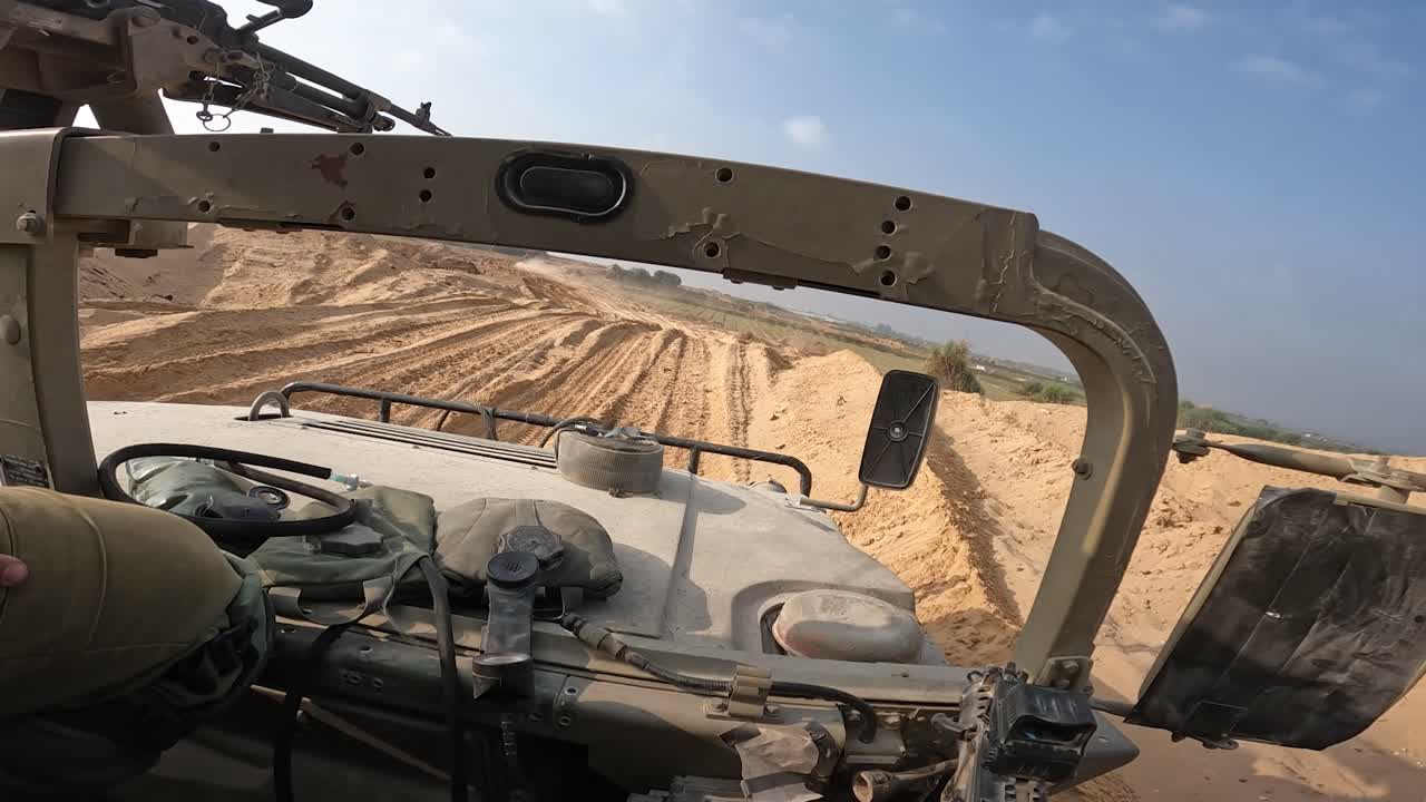 이스라엘 국방군 병사 가 가자 지구 를 순찰 하는 험비 차량 에 장착 된 기관총 을 준비 하고 있다