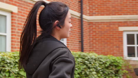 Rear-View-Of-Young-Woman-Exercising-Running-Along-Urban-Street-Wearing-Wireless-Earbuds-Before-Resting-2