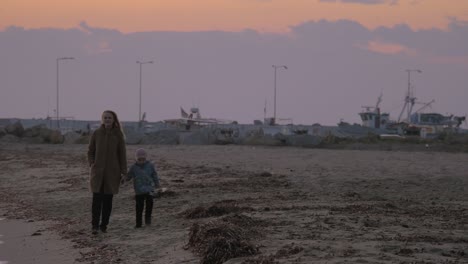 mother and child walking along the shore on cold day