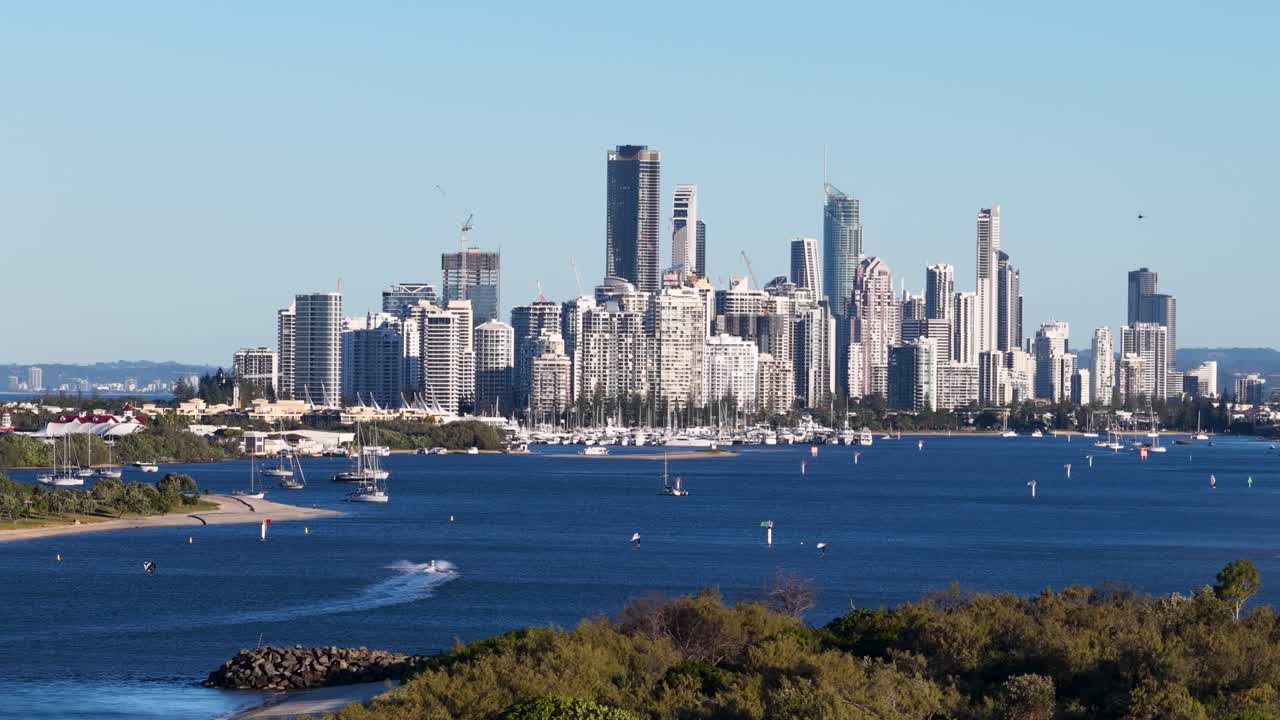 Drone captures Gold Coast skyline with boats on water, vibrant sunset lighting, and dynamic aerial movement