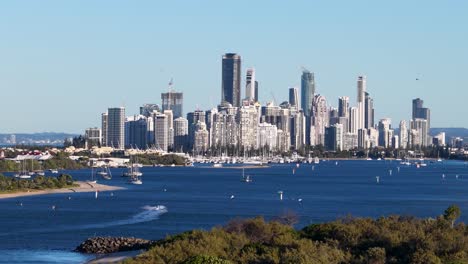 drone captures gold coast skyline with boats on water, vibrant sunset lighting, and dynamic aerial movement