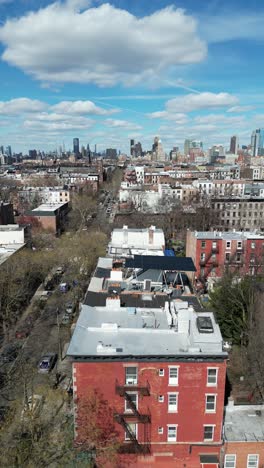 vertical drone side-tracking left shot over clinton street, brooklyn, featuring buildings, streets, and the urban landscape during the day.