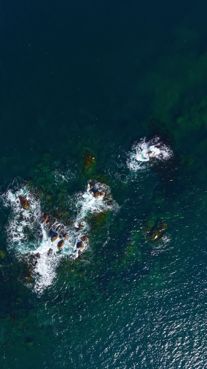 Waves crash over beautiful rocky formations in a serene ocean landscape under the sun