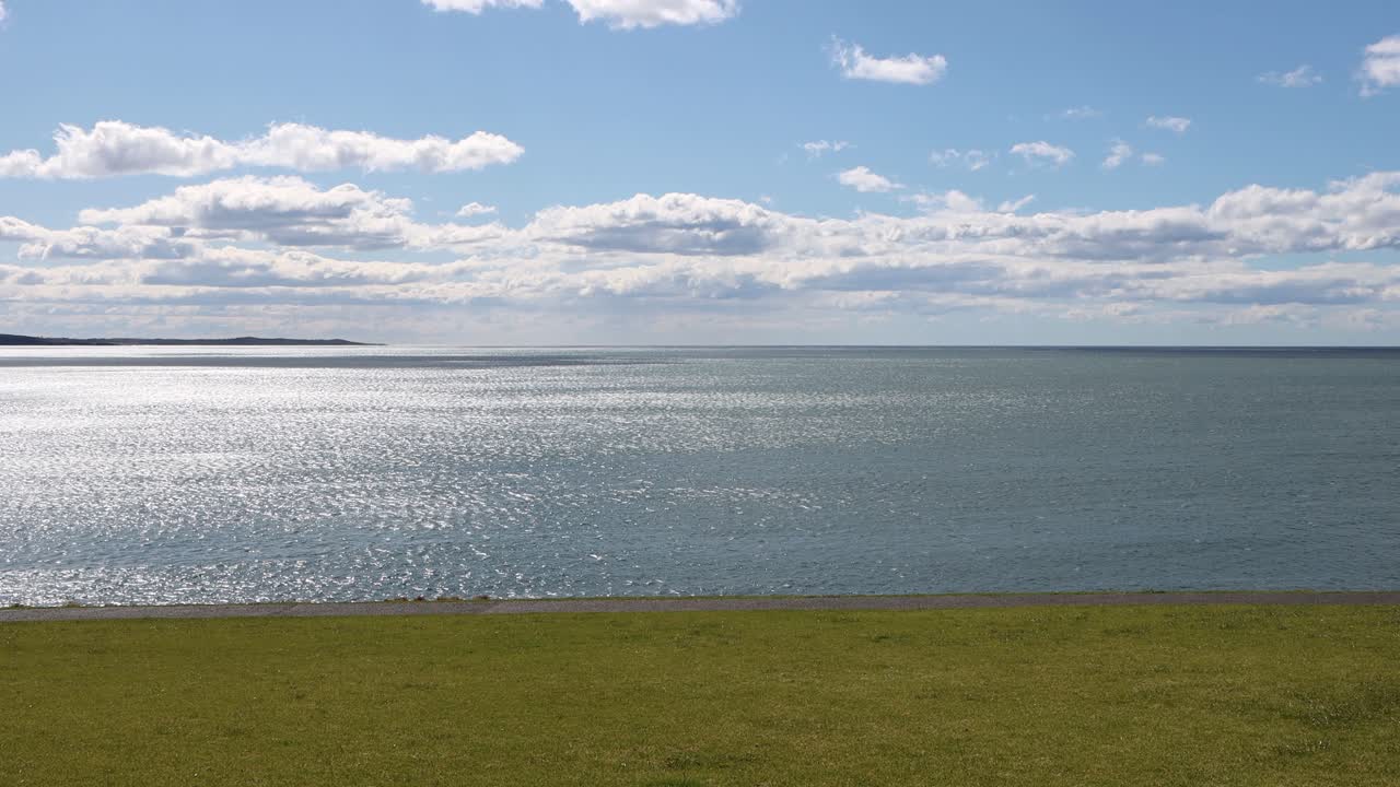 Couple walking along the grass on Kendalls Beach in New South Wales Australia during a cloudy sunny day, Locked shot