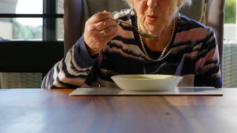 senior woman having soup on dining table at home 4k