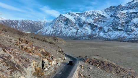 vista aérea trasera de un vehículo que conduce a través del valle de skardu en el frío desierto de sarfaranga de pakistán