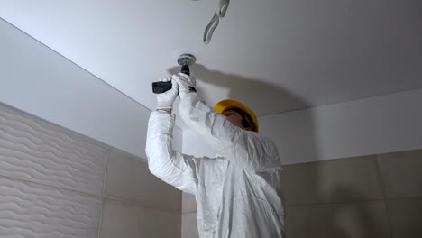 manual worker drilling hole in ceiling plasterboard for led lighting mounting