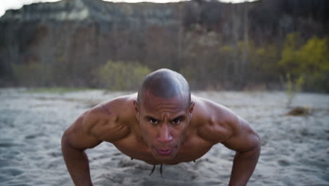 attractive and athletic man doing push-ups on a beach in slow motion