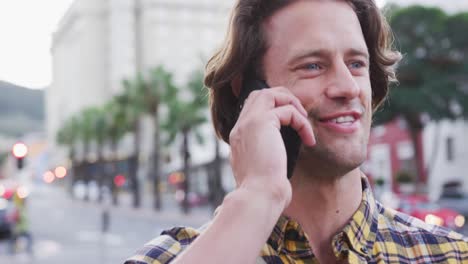 hombre caucásico hablando y usando su teléfono en una calle