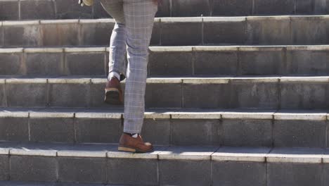 Legs-of-african-american-man-walking-upstairs-in-city