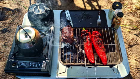 grilled red peppers and steak on charcoal barbecue with stove at campsite