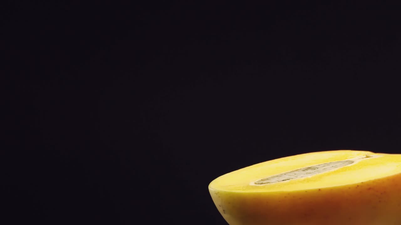 накрыть двумя половинками манго на черном фоне, семена манго разрезать пополам