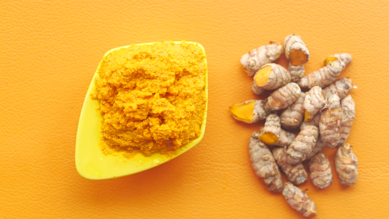 Radice e pasta di curcuma in una ciotola su sfondo bianco