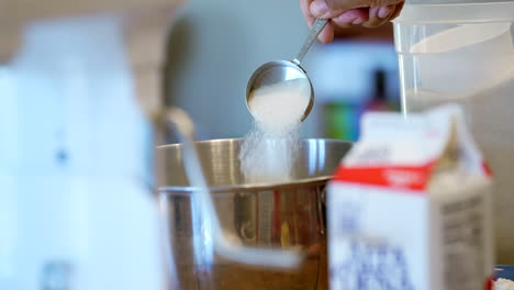 adding sugar to the mixing bowl for a homemade dessert made by mom - slow motion