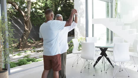 biracial man in a blue shirt is dancing with a biracial woman with short gray hair