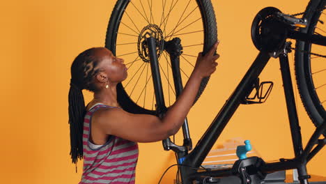 Ingeniero-Haciendo-Servicio-De-Bicicletas-En-El-Fondo-Del-Estudio,-Reemplazando-La-Rueda-Defectuosa