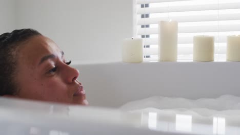 african american woman relaxing in the bath tub in the bathroom at home