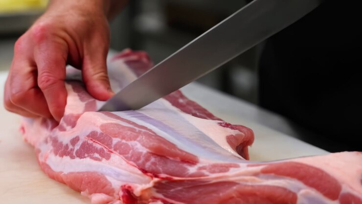 Chef Trimming Pork Belly With Knife, Closeup Of Hands Guiding Blade Along Fat Seam On Cutting Board