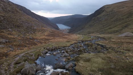 drone shot of a river flowing through the mountains into a lake