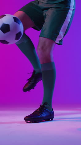 video vertical de un jugador de fútbol masculino caucásico con fútbol sobre iluminación rosa neón