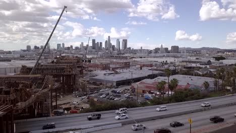 Aerial-view-from-right-to-left-of-Whittier-Blvd,-bridge-under-construction-with-Los-Angeles-skyline-in-the-distance