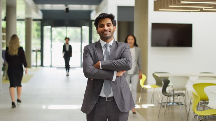 Portrait Of Businessman CEO Chairman Standing In Lobby Of Busy Modern Office Building