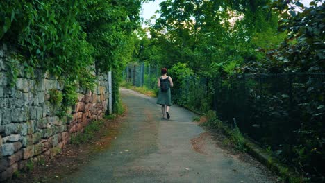 Back-view-of-young-caucasian-woman-walking-on-a-rural-dirt-road-in-nature