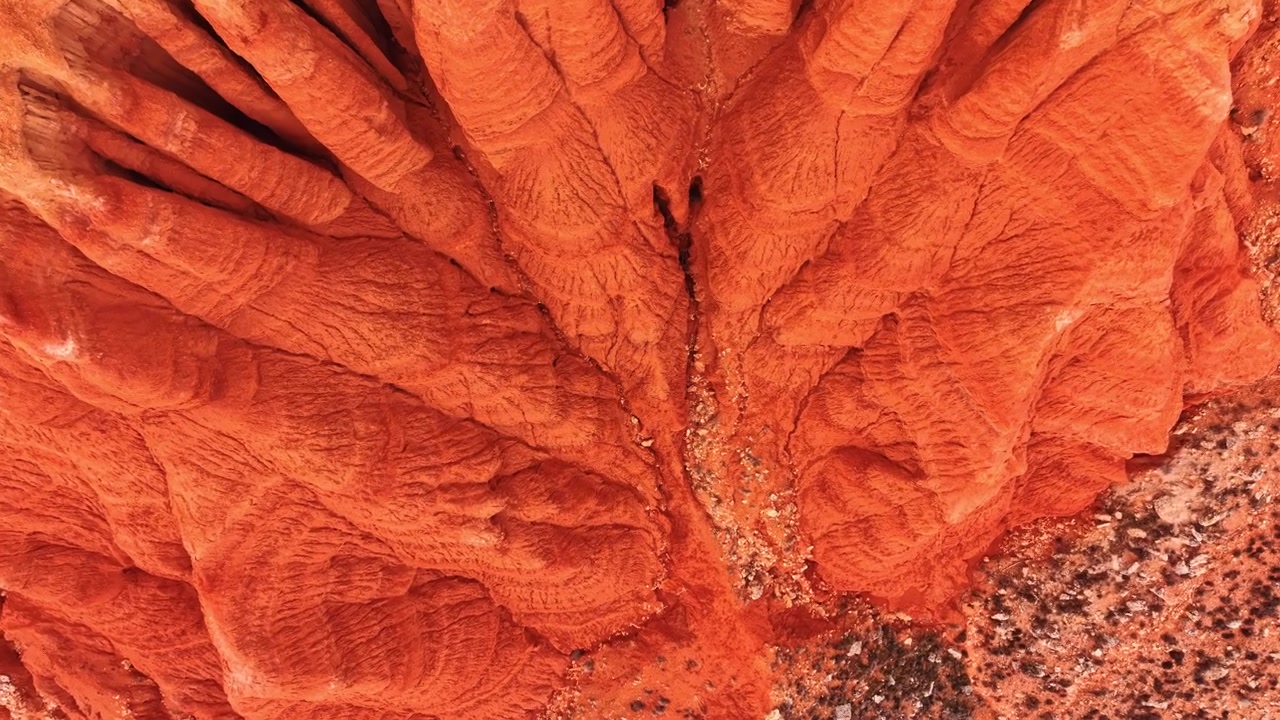 Vista drone di creste ramificate di argilla rossa e un letto di torrente secco, Spagna. Canali di erosione che si irradiano formando un motivo organico attraverso il terreno arancione.