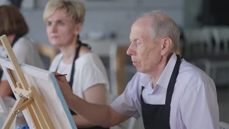 like senior friends attending together at a painting class. small group taking a variety of fun classes together. a group of elderly people attend a master class on drawing together spending time.