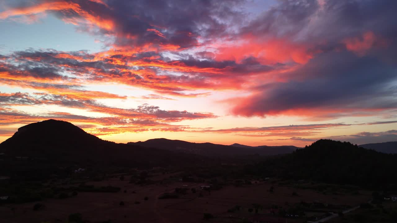 Vivid sunset over hills with colorful clouds creating a serene landscape