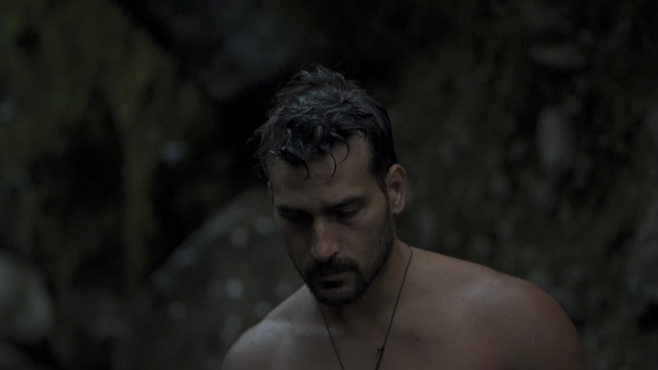 A man with a beard and wet hair is captured in a natural, candid moment walking on the Quebrada Gata trail