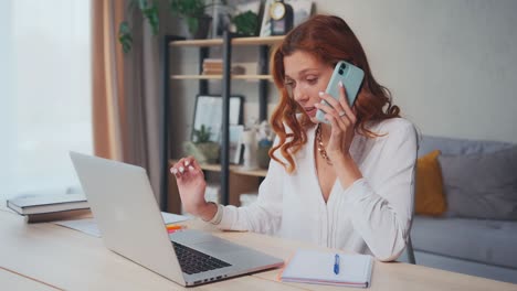 successful caucasian woman works on computer and speaks on phone at same time