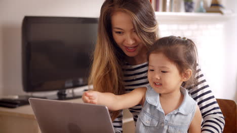 madre e hija ven películas en la computadora portátil en casa juntos