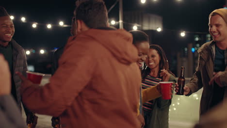 un grupo joven de amigos multirraciales divirtiéndose bailando juguetón juntos disfrutando de una fiesta en la azotea por la noche riendo celebrando la amistad
