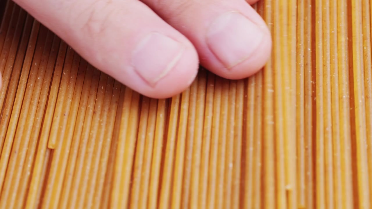 Primo piano di dita che toccano spaghetti secchi marroni