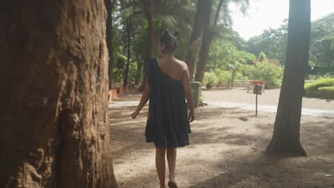 con un majestuoso árbol que proporciona sombra, una mujer camina con gracia, su rostro refleja una mezcla de preocupación y determinación