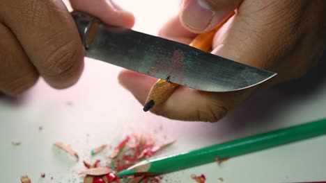 Footage-of-hands-slowly-sharpening-a-pencil-and-some-coloured-pencils-with-a-sharp-knife