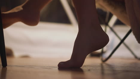 donna a piedi nudi che si riposa in una stanza d'albergo turistica in poltrona. godendo di un'atmosfera calma e confortevole la sera. arti del corpo femminile in rallentatore