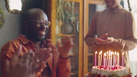 joyous man blowing candles on birthday cake at home celebration