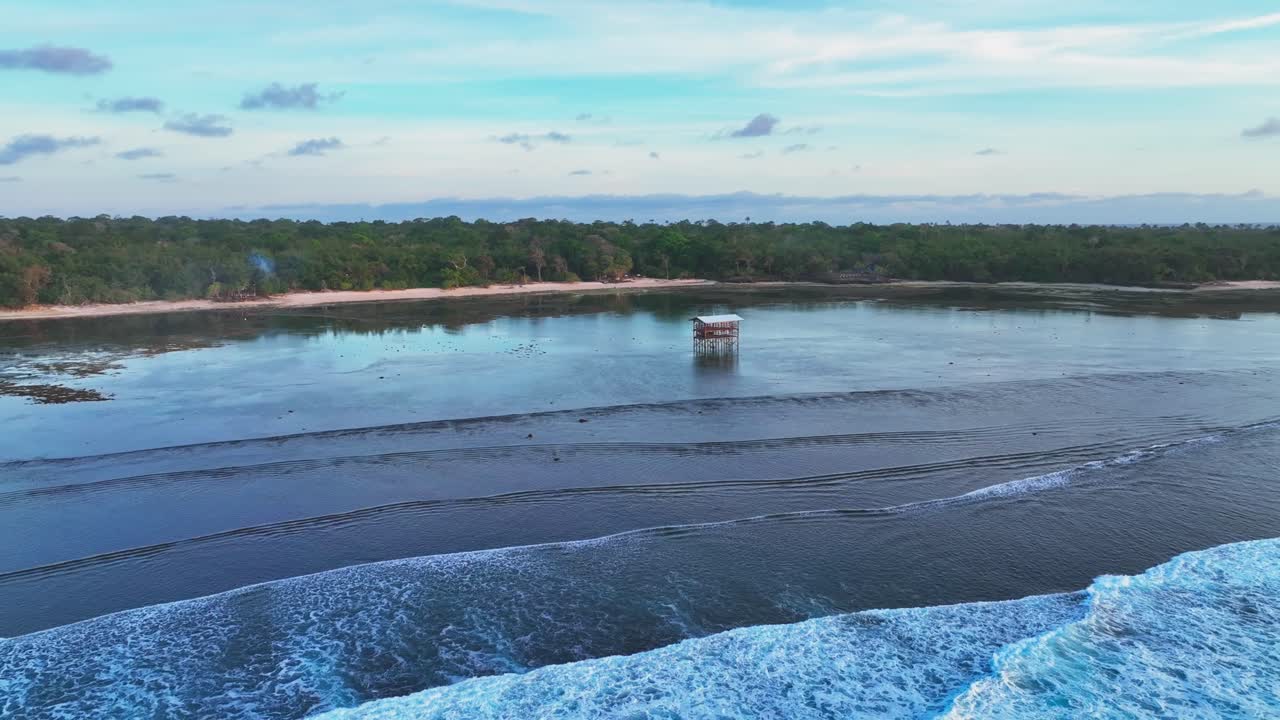 panning drone shot que muestra el campamento de surf de ecoturismo en la bahía de grajagan, en el borde de la selva del parque nacional de alas purwo, java, indonesia