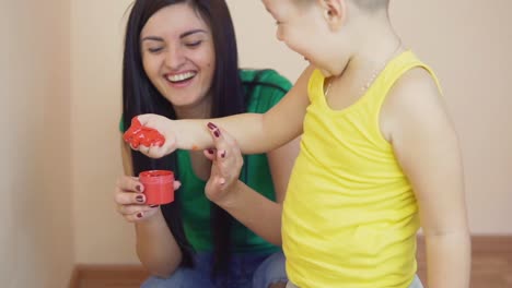 Madre-Feliz-Y-Su-Pequeño-Hijo-Están-Pintando-De-Color-Rojo-Con-Las-Manos-Sucias