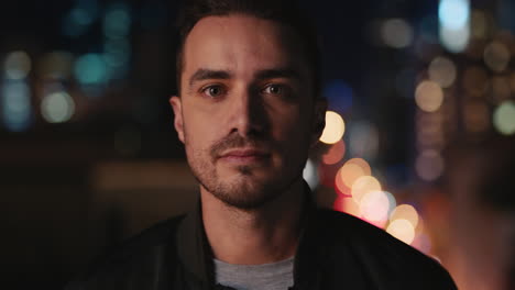 portrait of handsome young caucasian man on rooftop at night with bokeh city lights in urban skyline background