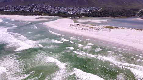 drone view of klein river estuary breaching into ocean as waves crash onto beach