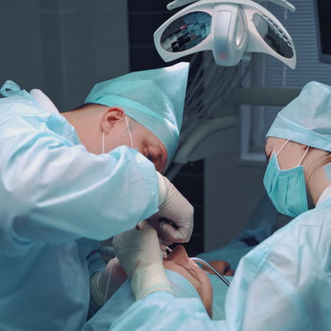 specialist man and female assistant in medical uniform work in dental office. stomatologists are making medical procedure on teeth for patient. oral treatment.