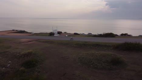 Cyclist-reaching-the-top-of-slope-front-to-Ocean-at-sunset