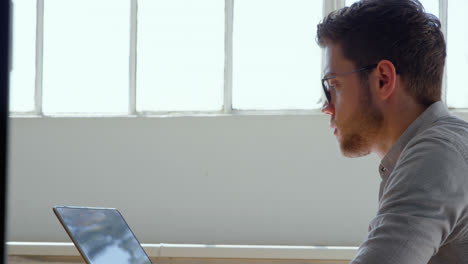 Side-view-of-young-caucasian-businessman-working-on-laptop-in-a-modern-office-4k