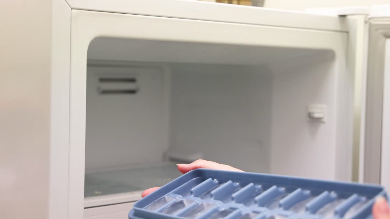 persona saca la bandeja de hielo del congelador