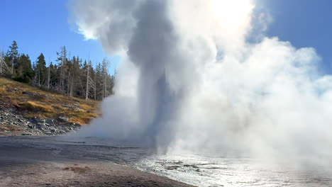 cinematic grand geyser old faithful sun glare sunrise sunset eruption explosion steam yellowstone national park observation deck upper geyser basin fall autumn beautiful blue sky slow motion pan