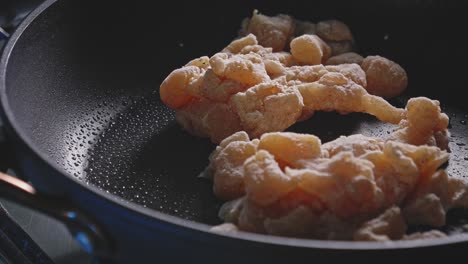 breast chicken meat cut in cubes and bread with flour stir fry on a pan