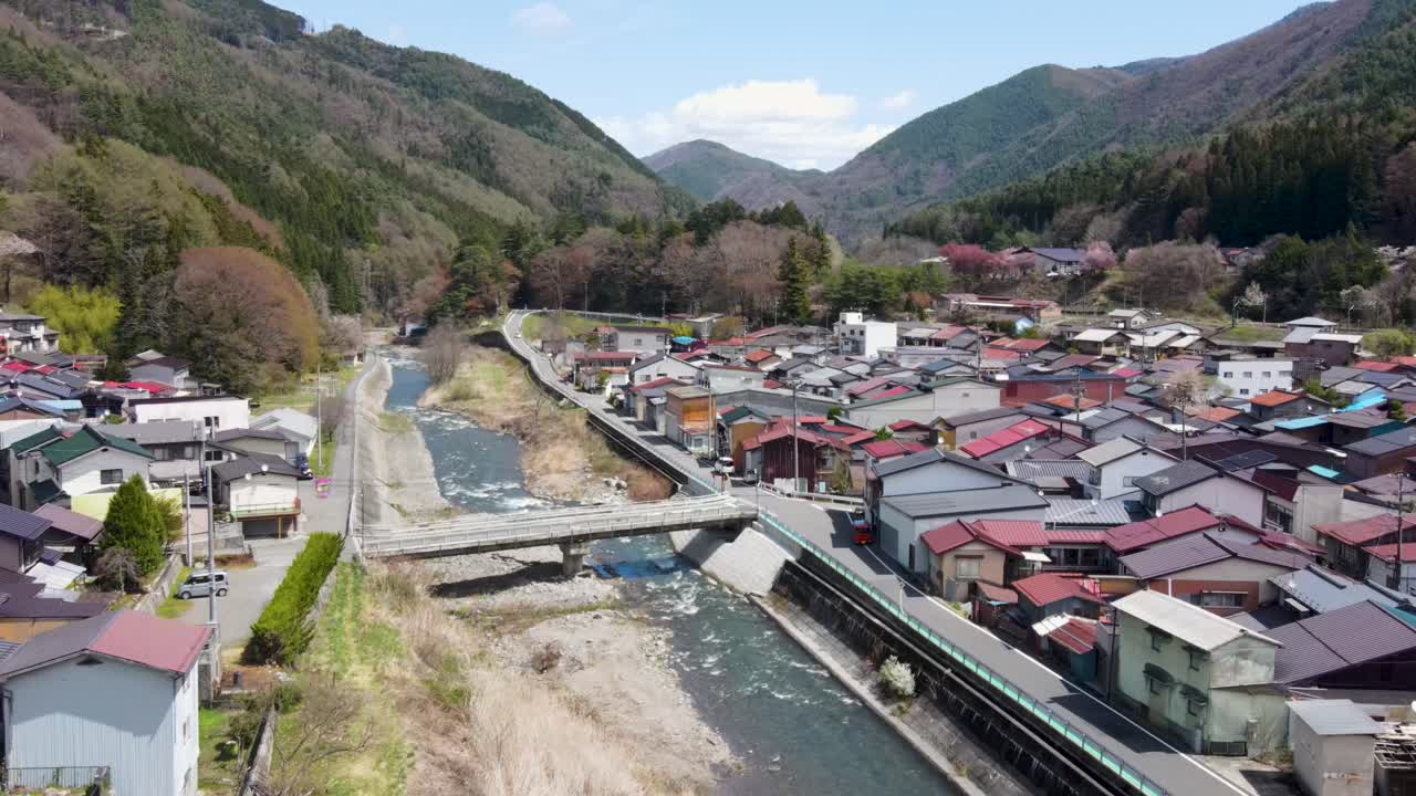 Aerial View Of Kiso-Hirasawa Town And Narai River With Cherry Blossom Trees In Kiso Valley Located In The Nagano Prefecture, Japan. Dolly Forward, Establishing Shot